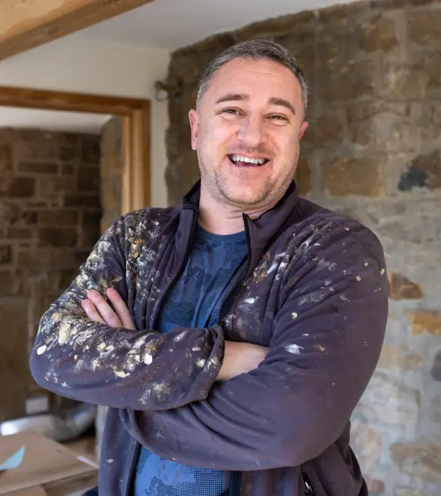 Decorator on site, smiling, arms crossed